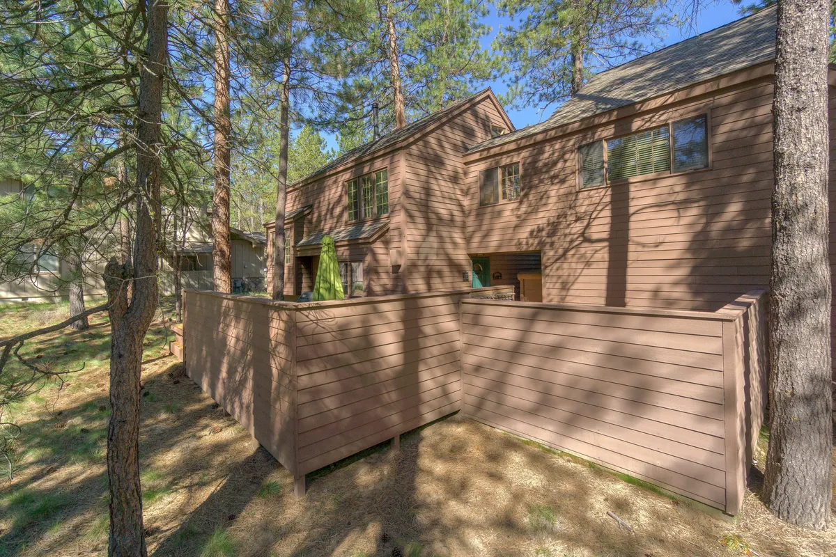 The image shows the cabin’s exterior surrounded by lush trees and a fenced area, ideal for safe play and relaxation. The natural environment hints at possibilities for outdoor games, family gatherings, and kids enjoying the yard.