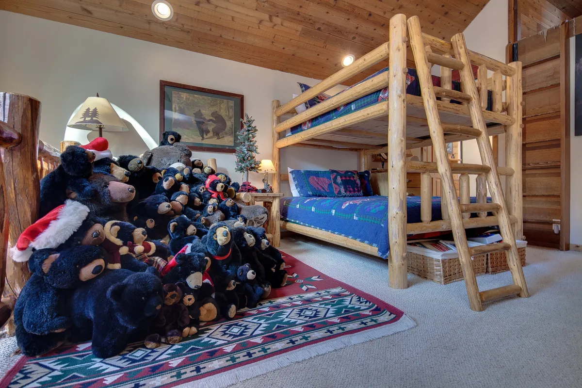 A playful and inviting loft scene with a bunk bed dressed in a colorful quilt, surrounded by wooden accents and a cheerful pile of teddy bears. The lighthearted mood and kid-friendly details make it an ideal representation of the Pyramid bunks loft mentioned in the section.