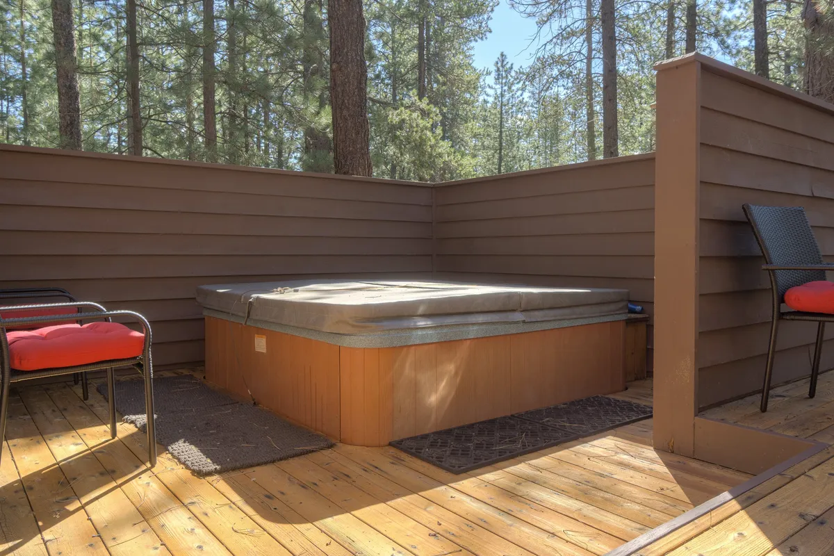 A private hot tub is nestled among the trees, with a nearby seating area, offering a tranquil space for relaxation and stargazing after a day of adventure.